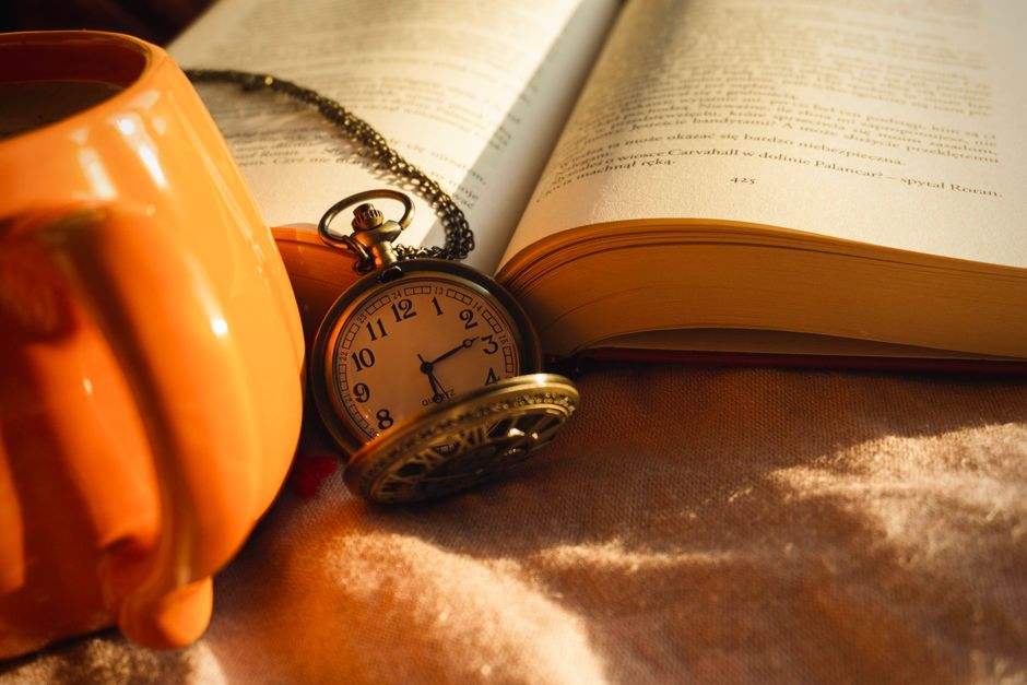 Aesthetic still life featuring a vintage pocket watch, an open book, and a warm cup, perfect for cozy autumn vibes.